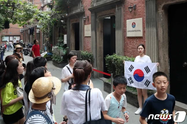 一名韩国女游客在临时政府旧址前举韩国国旗留念