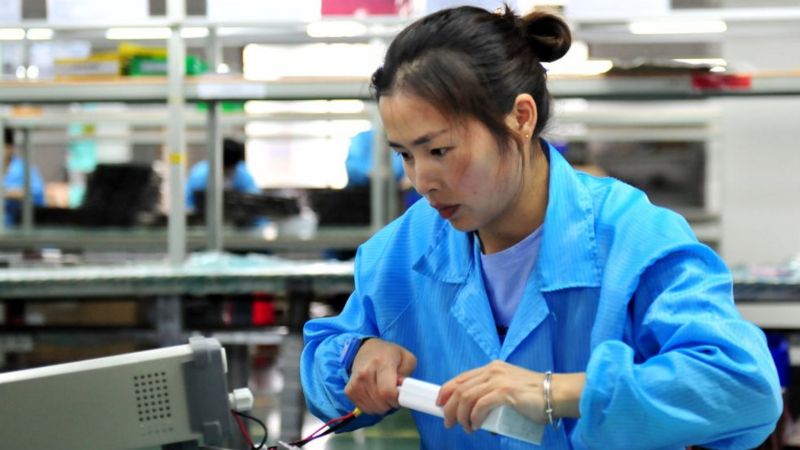中国女工在生产线上测试锂电池产品的电源连接