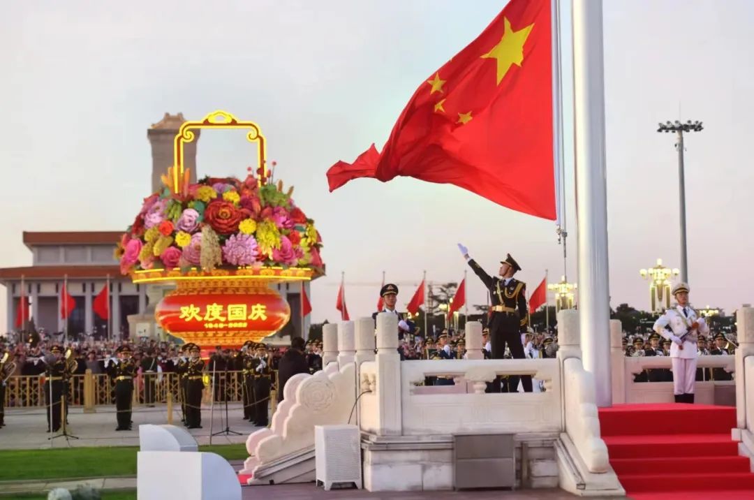 升旗手高高扬起国旗，鲜艳的五星红旗迎风招展