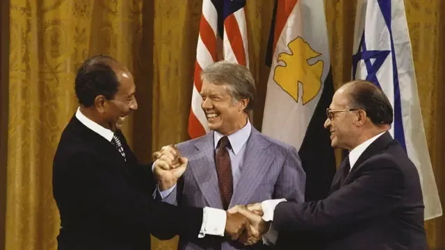 1978年9月18日，在白宫，卡特与埃及总统安瓦尔·萨达特和以色列总理梅纳赫姆·贝京在签署戴维营协议后握手 ...